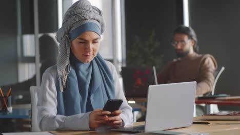 Young-Muslim-Businesswoman-Using-Smartphone-at-Work